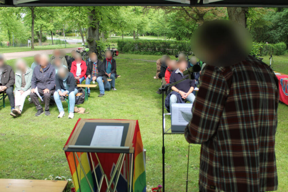 Eine Person steht mit dem Rücken zur Kamera, im Hintergrund sind die Besucher*innen der Veranstaltung zu sehen.